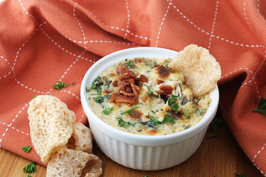 white dish with bacon and roasted garlic spinach dip served with pork rinds