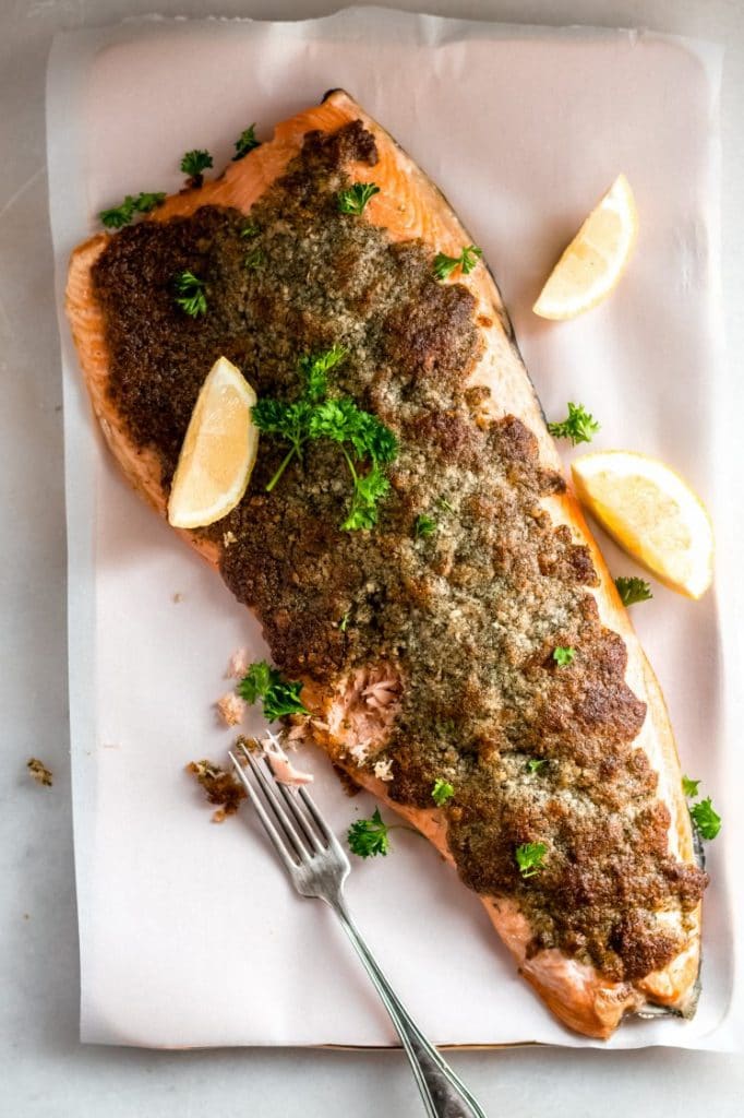 baked parmesan crusted salmon poked through with a fork to reveal perfectly cooked fish