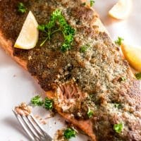close up photo of keto parmesan crusted salmon with lemon wedges on a baking tray