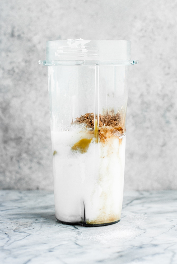 Chocolate Fat Bomb Smoothie ingredients poured into a blender atop a marble kitchen counter