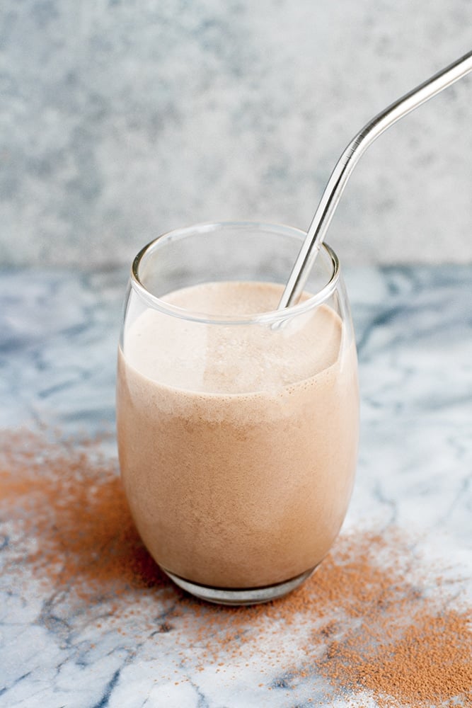 hero shot of chocolate fat bomb smoothie in a glass atop a marble kitchen counter