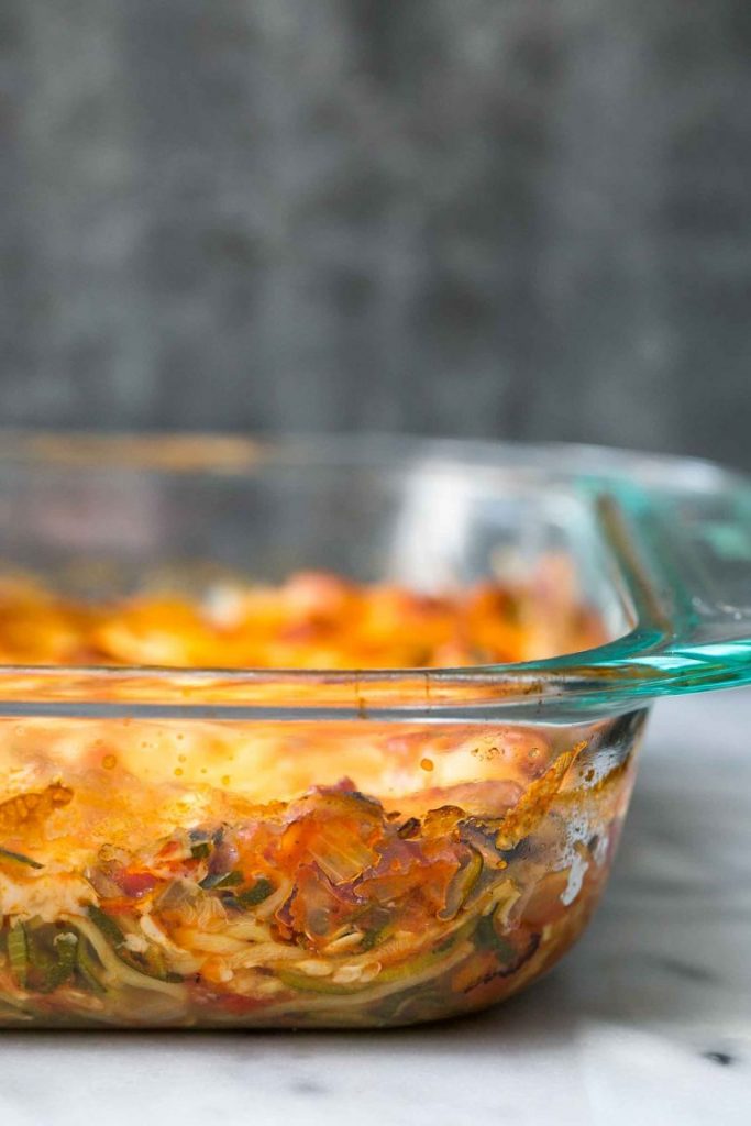 side view of cheesy baked zucchini noodle casserole in a glass dish