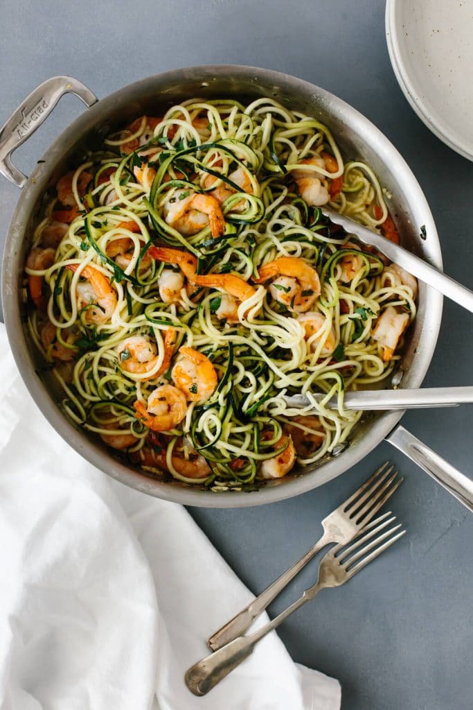 zucchini pasta with lemon garlic shrimp in a metal skillet with tongs