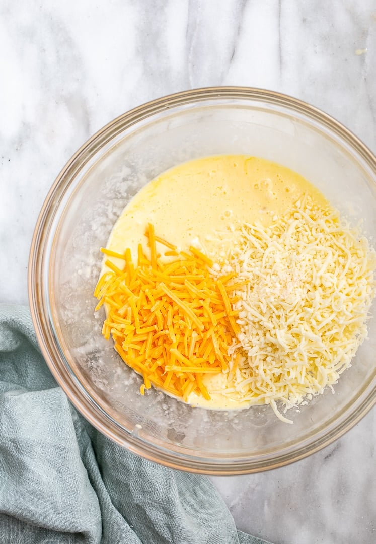 a medium bowl with egg batter, mozzarella and cheddar