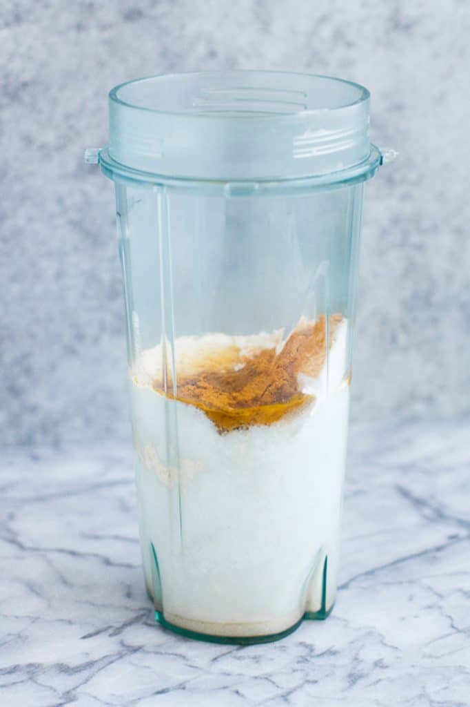 food processor cup with smoothie ingredients atop a marble kitchen counter