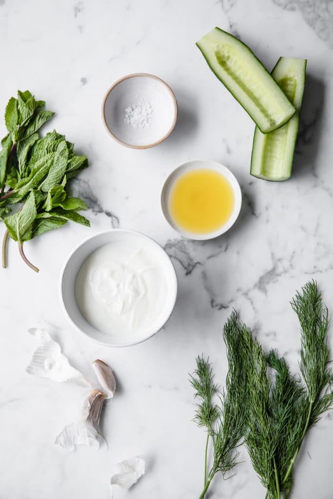 tzatziki ingredients arranged atop a marble kitchen counter