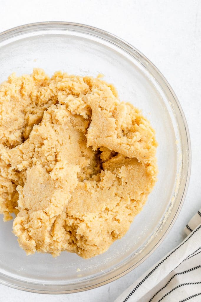 keto cookie dough in a glass mixing bowl atop a marble kitchen counter