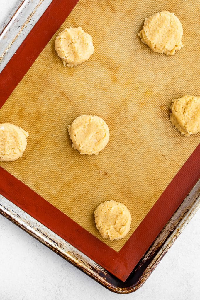 low carb cookie dough formed into cookies atop a silicone mat-lined baking tray
