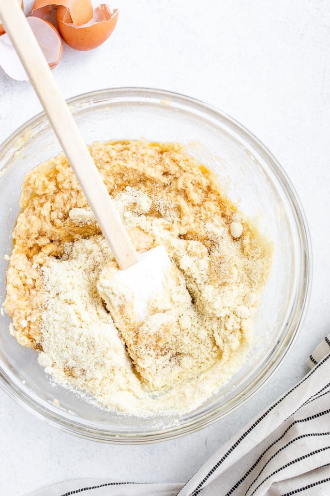 wet and dry ingredients for low carb cookies in a mixing bowl with a spatula