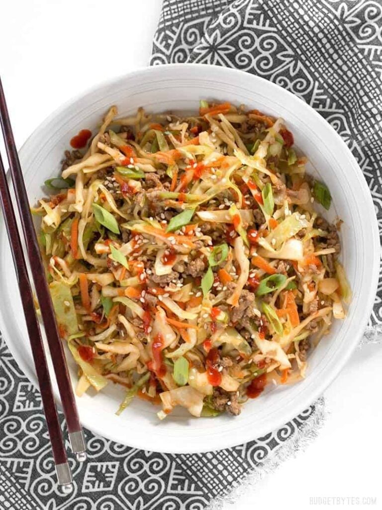 a bowl of beef and cabbage stir fry with chopsticks