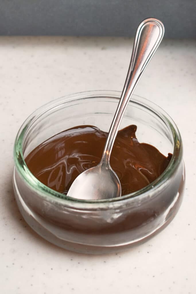 melted dark chocolate in a small bowl and a teaspoon