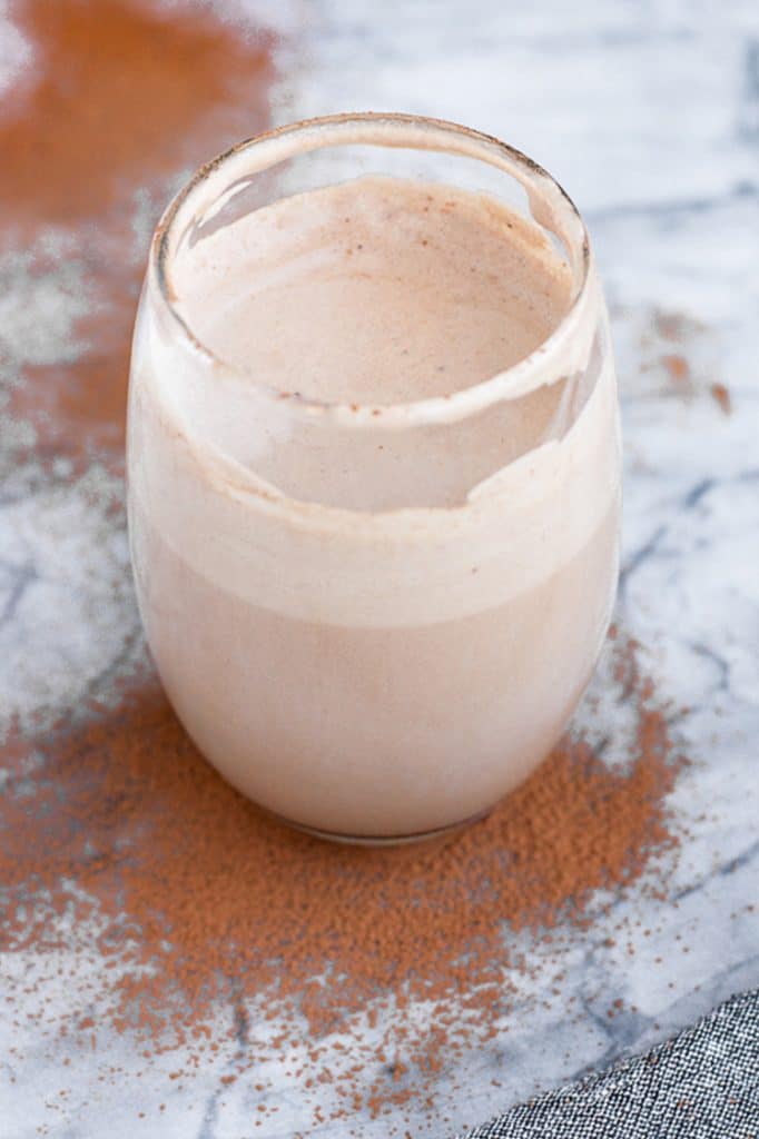 close up shot of a glass of keto mocha smoothie on a marble kitchen counter