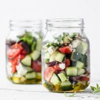 featured recipe image - 2 jars of low carb greek salad atop a marble kitchen counter