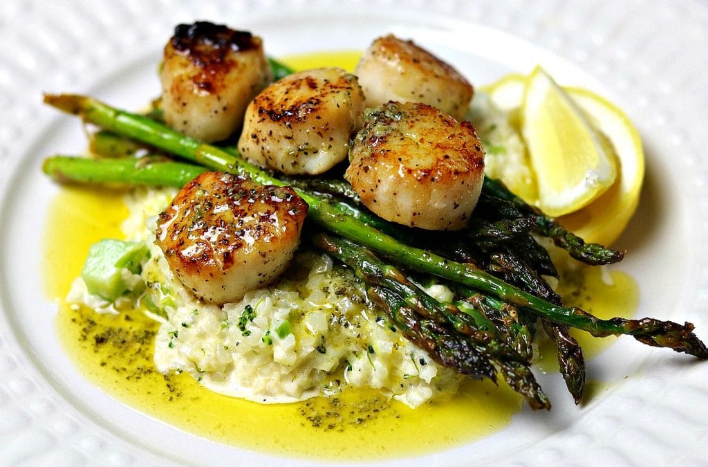 seared scallops atop a scoop of cauliflower rice risotto and cooked asparagus