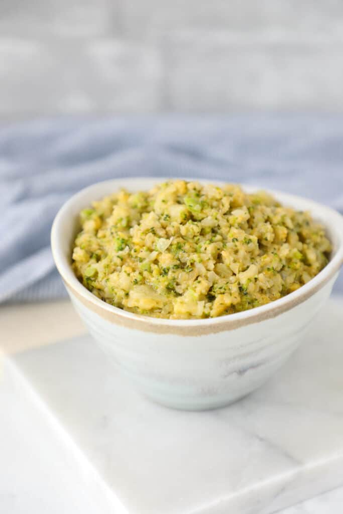 a bowl of Keto Cheesy Broccoli & Cauliflower Rice atop a marble kitchen counter