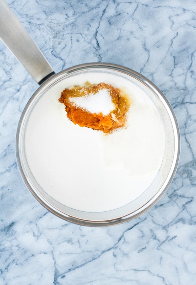 overhead shot of heavy cream, pumpkin puree, monk fruit sweetener, and gelatin powder in a saucepan