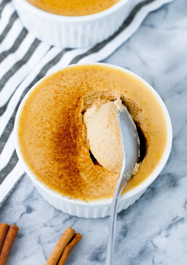 Close-up shot of Pumpkin Pie Panna Cotta being scooped by a spoon atop a marble kitchen counter