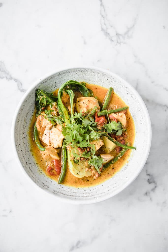 a bowl of Low- Carb Salmon Curry over-head shot atop a marble kitchen counter