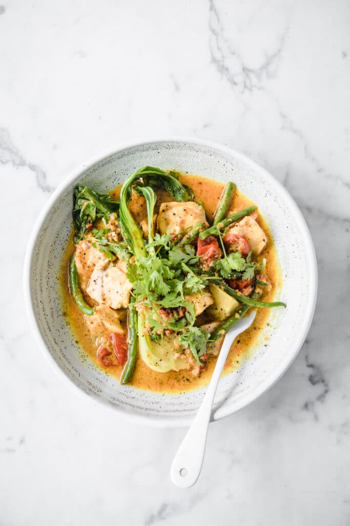 Keto Salmon Coconut Curry: a bowl of Low-Carb Salmon Curry with a fork atop a marble kitchen counter