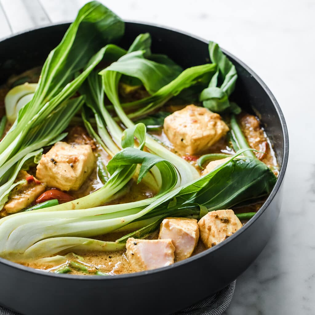 Keto Salmon Coconut Curry: Low Carb Salmon Curry in a pan atop a marble kitchen counter