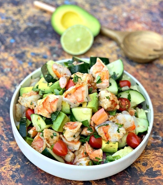 a bowl of shrimp and avocado ceviche salad atop a wooden table