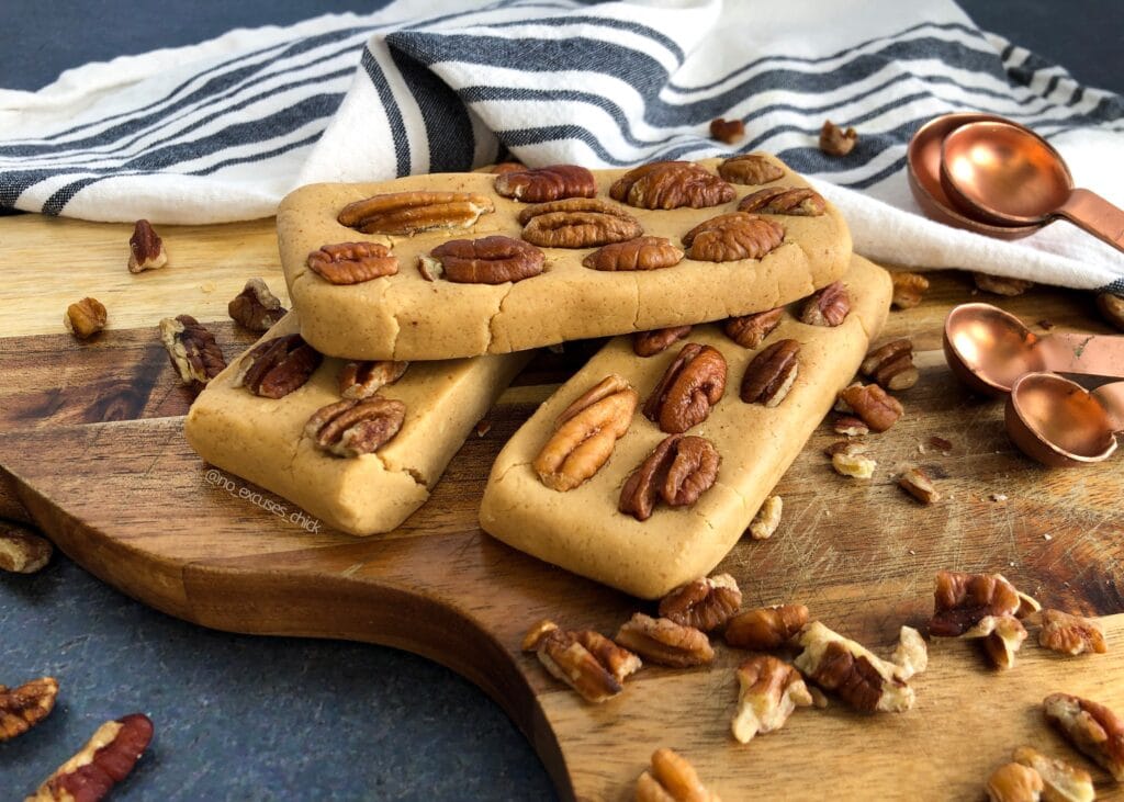 3 butter pecan protein bars stack on top of each other on  wooden chopping board