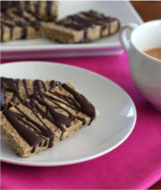 a ceramic plate with 2 peanut butter chia seed protein bars on top atop a red table