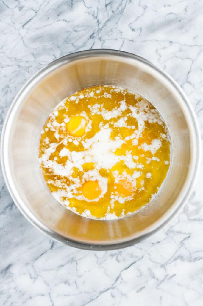melted butter, egg, egg whites and vanilla extract in a mixing bowl atop a marble kitchen counter