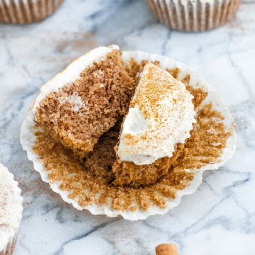 keto cinnamon roll muffin broken in half atop a marble kitchen counter
