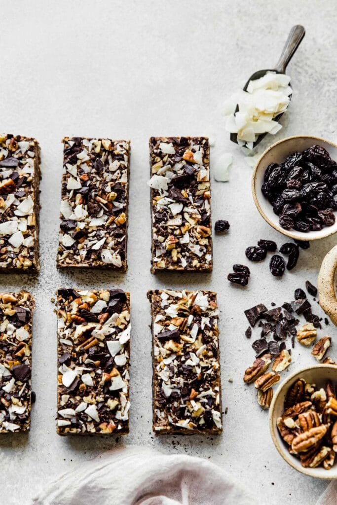 6 pecan low carb protein bars line up in a row on top of a parchment paper