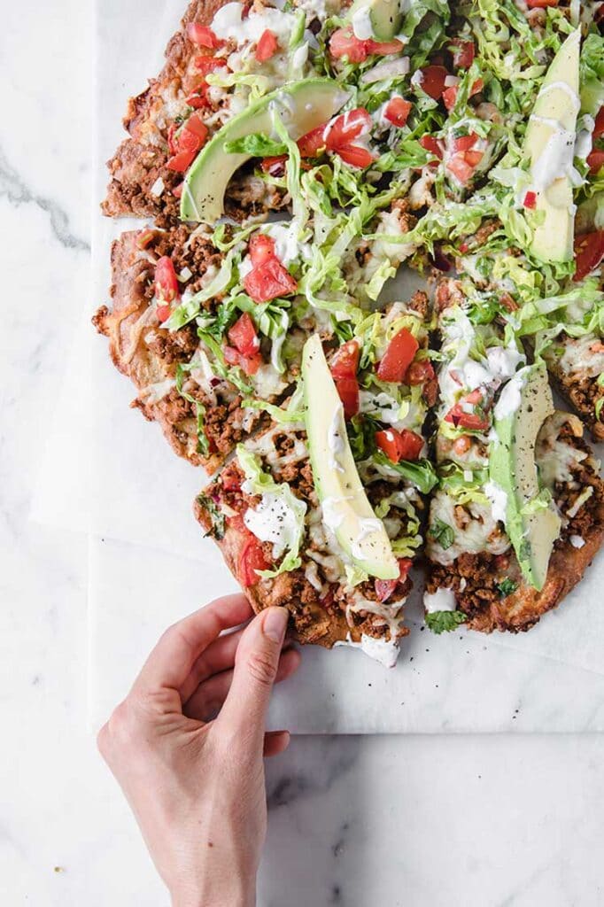 a hand takign a slice out of keto fathead taco pizza