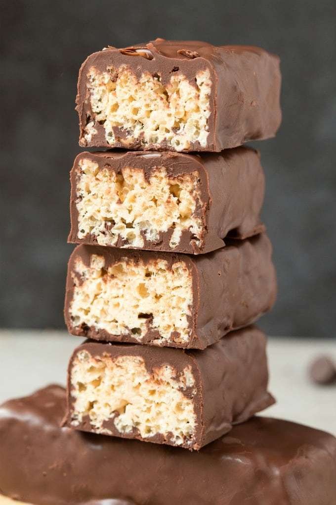 2 bars of keto protein crunch bars sliced in half stacked together on top of a bar of protein crunch bar