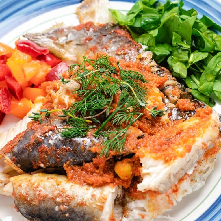 one plate of baked whole catfish garnished with herbs and spices