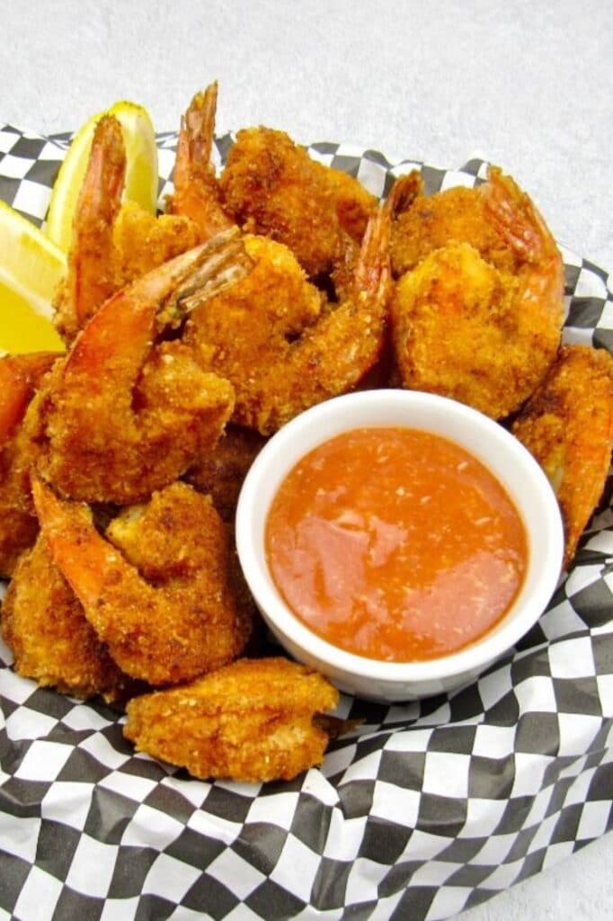 a batch keto fried shrimp with cocktail sauce and lemon slices on the side atop a marble kitchen table