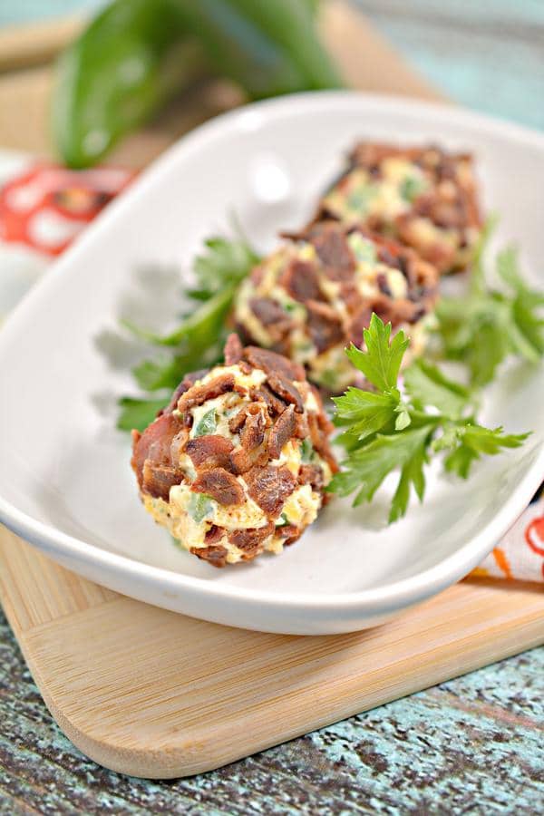 3 keto jalapaeño ranch cream cheese fat bombs garnished with herbs on a plate atop a wooden table