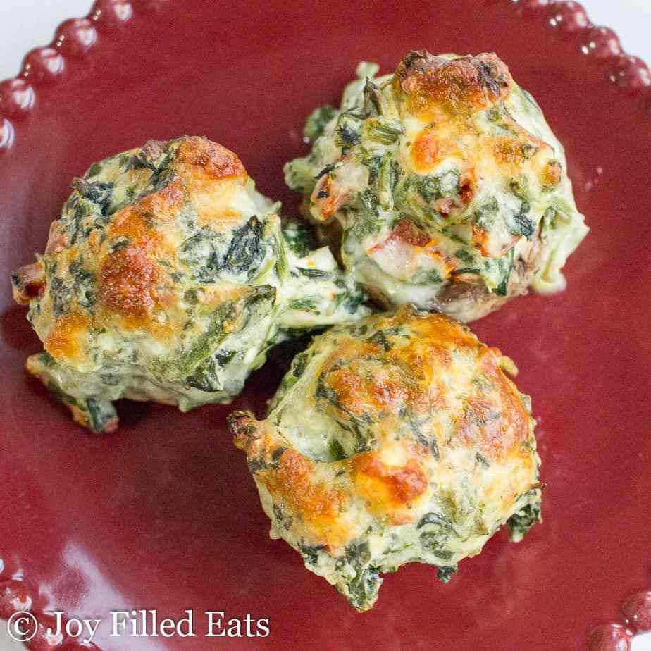 three spinach stuffed mushrooms  sun dried tomatoes on a red plate