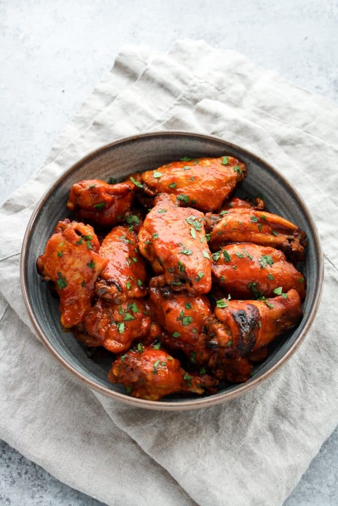 Instant Pot Low-Carb Sweet & Spicy Barbecue Chicken Wings in a ceramic bowl with a cloth table napkin underneath