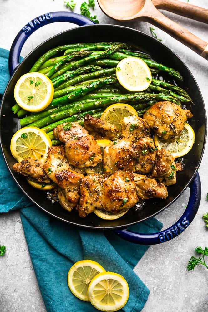 overhead shot of instant pot lemon garlic chicken on a pan garnished with lemon slices and asparagus atop a kitchen counter