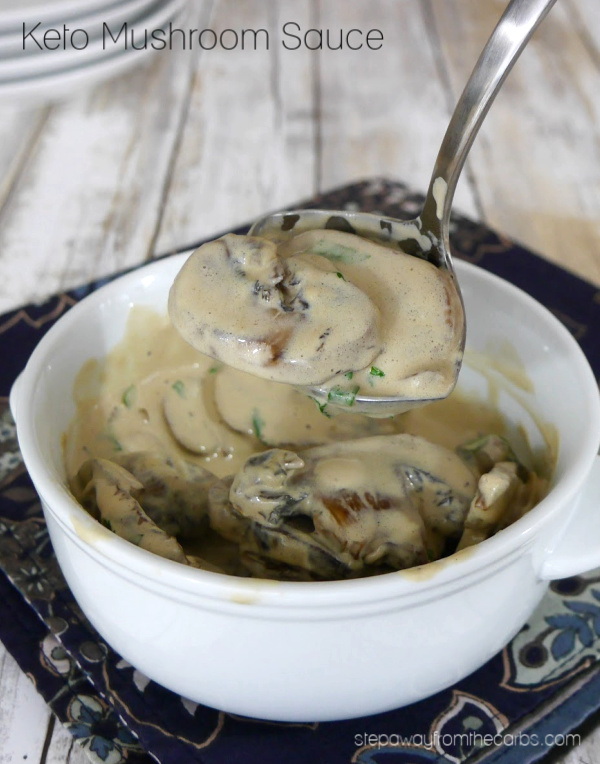 bowl of keto mushroom sauce being scooped by a spoon atop a wooden table