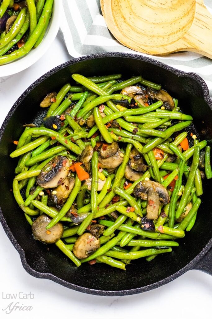 sauteed green beans and mushroom on a pan atop a marble kitchen table