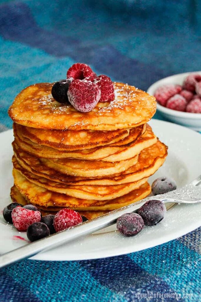 a stack of low carb pancakes topped with assorted berries on a plate