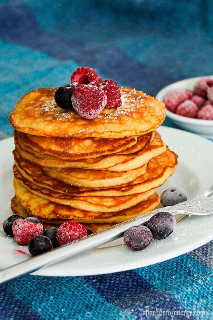 a stack of low carb pancakes topped with assorted berries on a plate