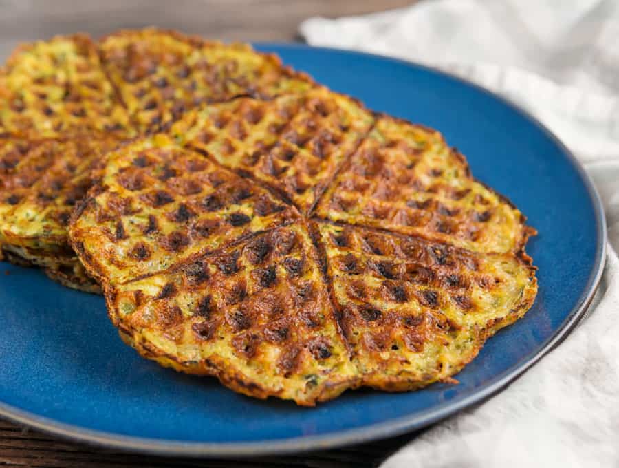 two zucchini chaffles on top of each other on a plate atop a marble table