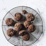 Close-up shot of nut-free keto chocolate sea salt cookies resting on a baking rack, atop a marble countertop.