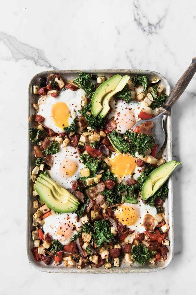 a baking tray of keto sheet pan breakfast hash with a spatula on the side atop a marble kitchen counter