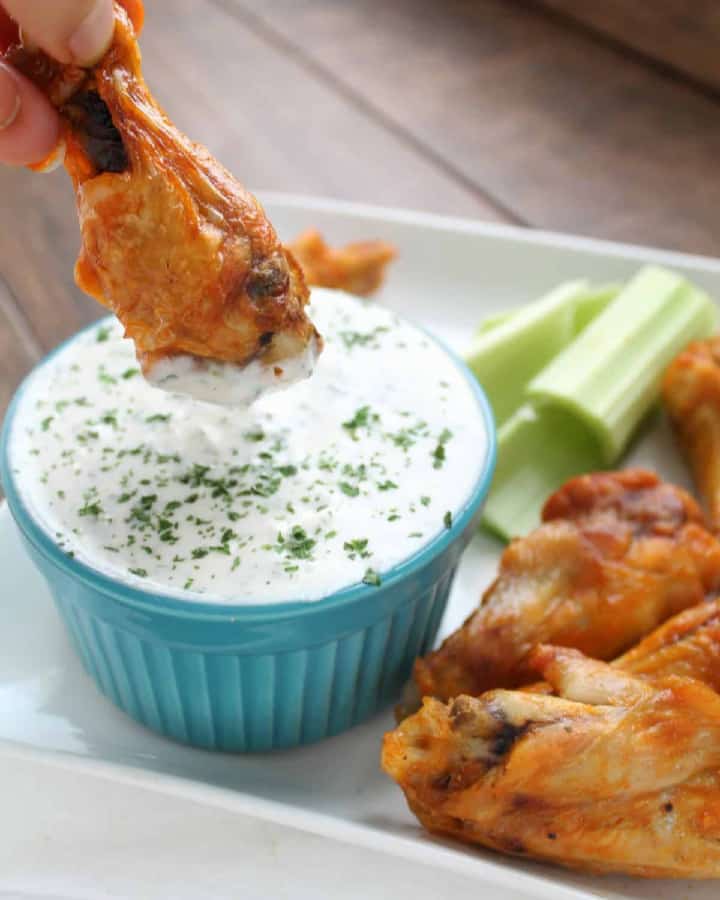 crispy baked keto chicken wings being dipped in ranch dressing