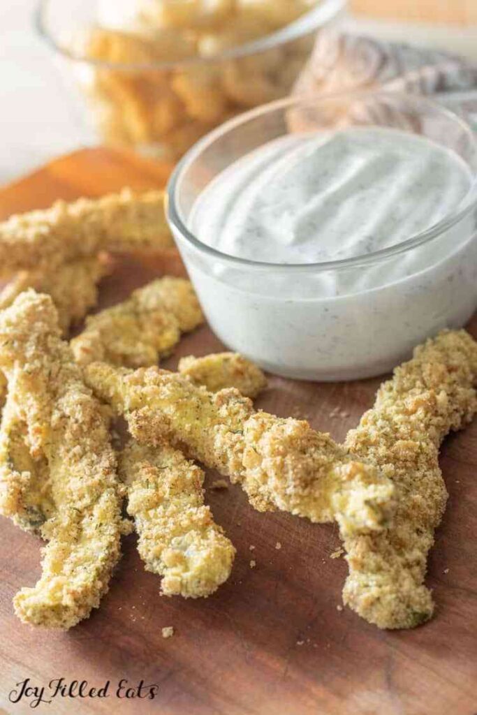 fried pickels on a wooden plate with mayo dip