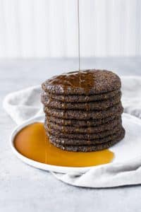 a stack of vegan keto baked pancakes on a plate drizzled with lakanto maple flavored syrup