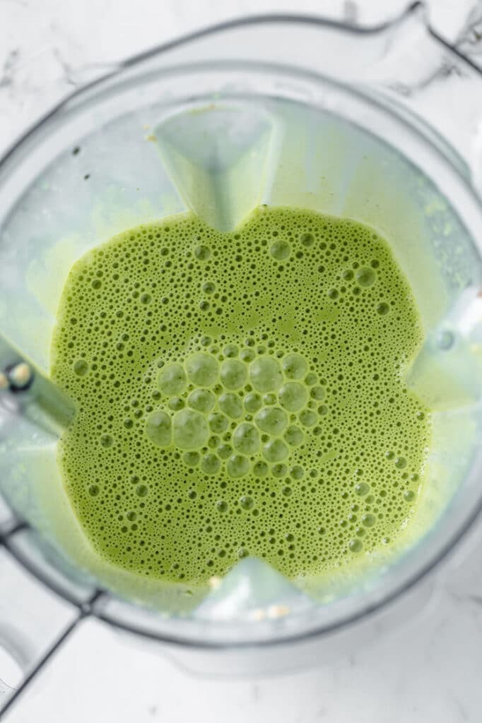 blended coconut milk and spinach in a blender atop a marble kitchen table