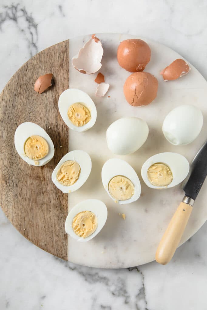 halved peeled hard boiled eggs on a circle marbled chopping board